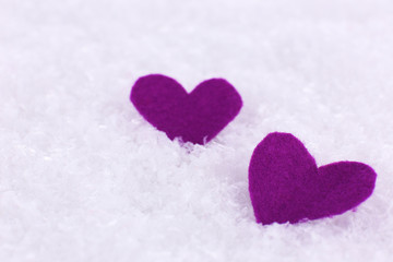 Little felt hearts on snowy background