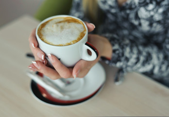 Cappuccino with  in manicured hands of woman