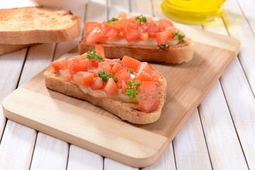 Delicious bruschetta with tomatoes on cutting board close-up