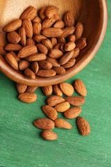 Almonds in bowl on color wooden background
