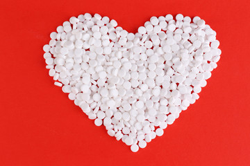 Heart of pills on red background