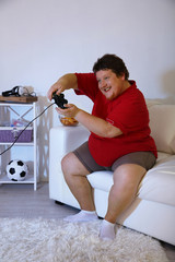 Fototapeta na wymiar Fat man playing video games on home interior background
