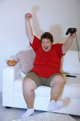 Fototapeta na wymiar Fat man playing video games on home interior background