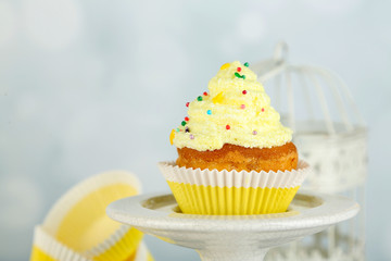 Tasty cup cake with cream on grey wooden table