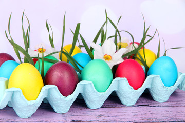 Colorful Easter eggs with grass and flowers in tray