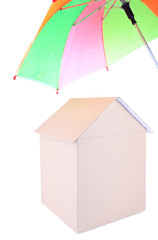 Cardboard house with umbrella isolated on white