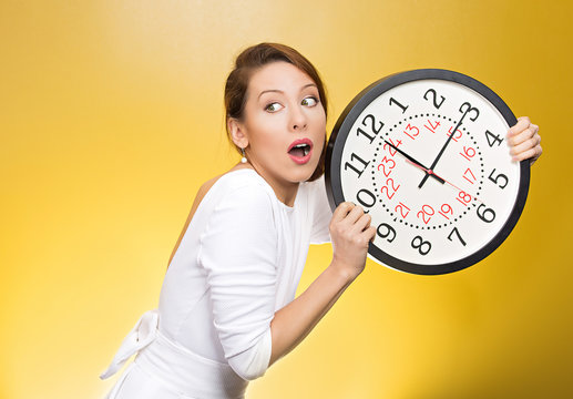 Running out of time. Girl holding wall clock, yellow background 