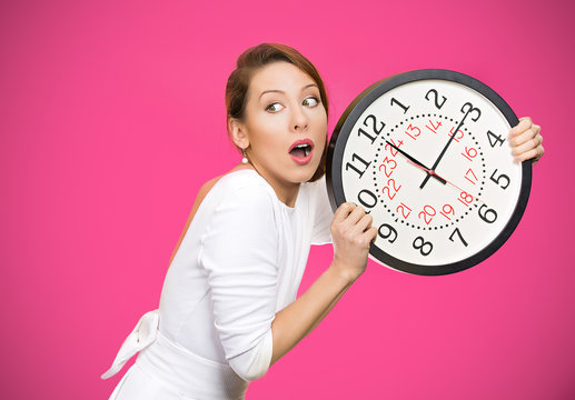 Running out of time. Girl holding wall clock on pink background 