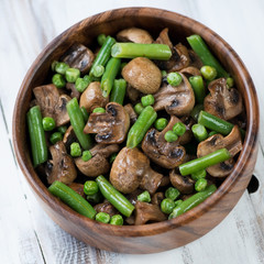 Wooden bowl with roasted champignons and vegetables