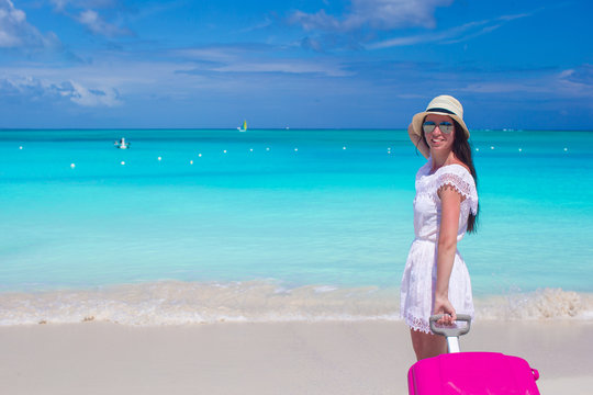 Young beautiful woman with colorful luggage on tropical beach