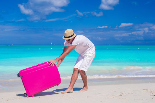 Young traveler with his luggage on a tropical beach