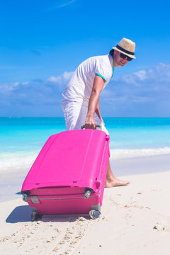 Young traveler with his luggage on a tropical beach