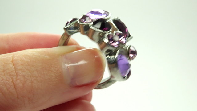 jewelery ring with purple crystals putting on the finger