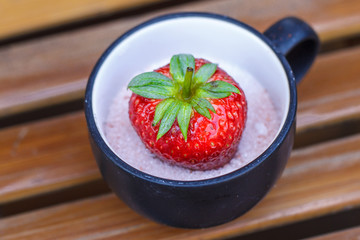 Strawberry in a cup of dessert on bamboo table