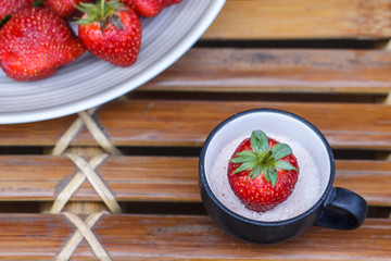 Strawberry in a cup of milk on bamboo table