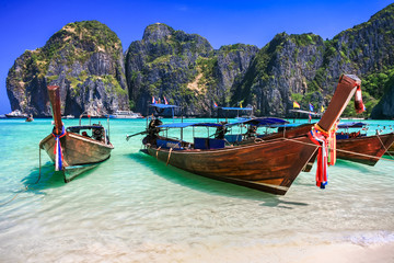 Long tail boat on white sand beach with crystal clear sea - 64310415