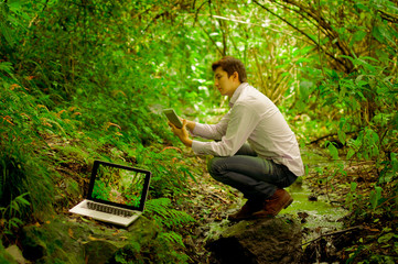 Fototapeta premium man using tablet and personal computer in the jungle