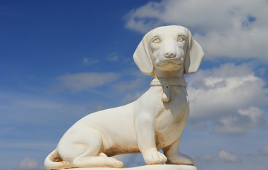 Obraz na płótnie Canvas Statue de chien basset sur un fond de ciel bleu nuageux