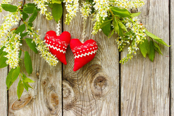 Czerwone serca na drewnianym tle wśród kwiatów