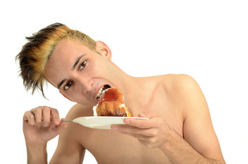 Hungry young man eating a cream cake, topless man tasting sweets