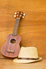 Fototapeta premium The ukulele and a hat is placed on a wooden floor.