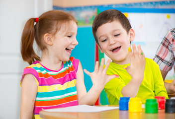 Fototapeta premium Two happy children drawing with colorful paints