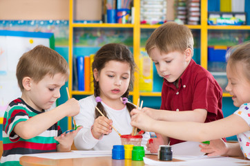 Cute children drawing with colorful paints at kindergarten