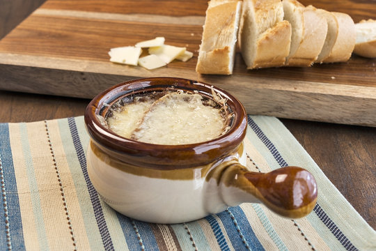 Crock full of traditional French Onion Soup with melted cheese