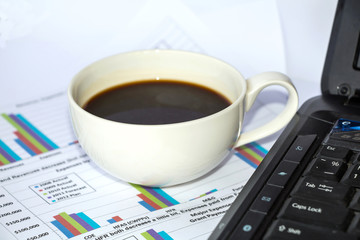 Business papers with charts and graphs and with a cup of coffee.