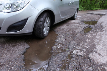 Damaged road full of cracked potholes in pavement - 64322257