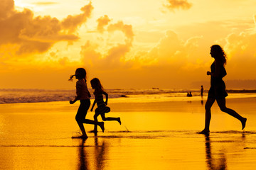 Happy family playing at the beach in the dawn time