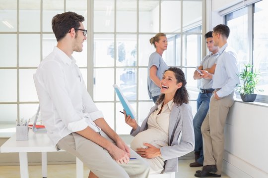 Pregnant businesswoman laughing with colleague
