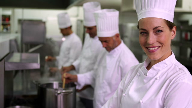 Head chef smiling at camera with team behind her