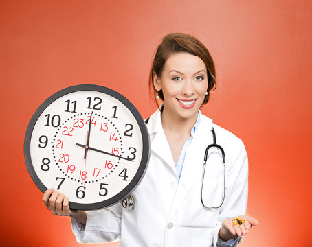 Time for your meds. Doctor holding wall clock and pills
