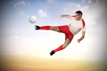 Fototapeta premium Composite image of fit football player playing and kicking