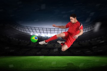 Composite image of fit football player jumping and kicking
