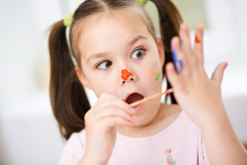 Portrait of a cute girl playing with paints