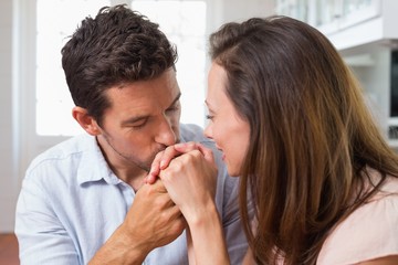 Loving man kissing womans hand at home