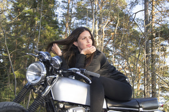 Sexy female woman on a motorcycle posing in a forest