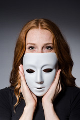 Redhead woman iwith mask in hypocrisy consept against grey backg