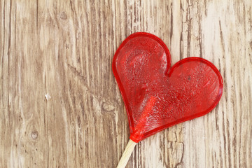 Heart shaped lollipop on wooden surface with copy space
