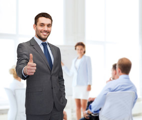 handsome buisnessman showing thumbs up in office