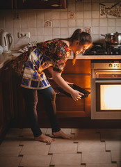 housewife holding cookies on pan near oven