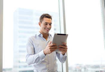 smiling businessman with tablet pc in office