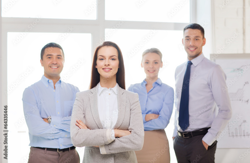 Sticker smiling businesswoman in office with team on back