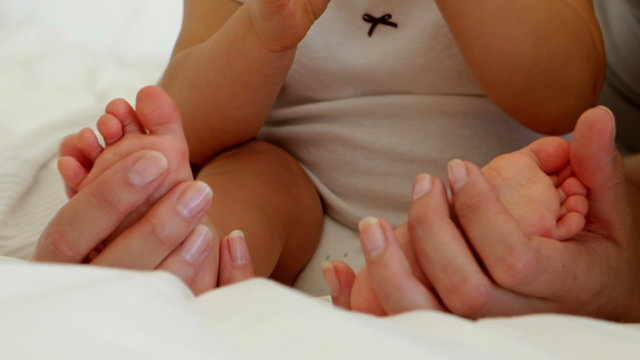 Mother touching her baby daughters tiny toes