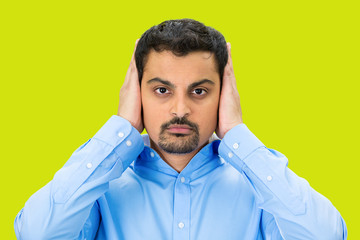 Hear no evil concept. Man covers his ears, green  background 