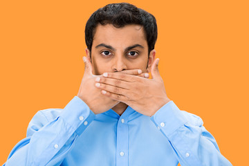 Speak no evil, man covering mouth, orange background 