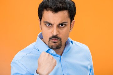 Portrait angry man with fist up, isolated orange background 