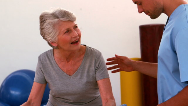 Physiotherapist helping patient walk with parallel bars